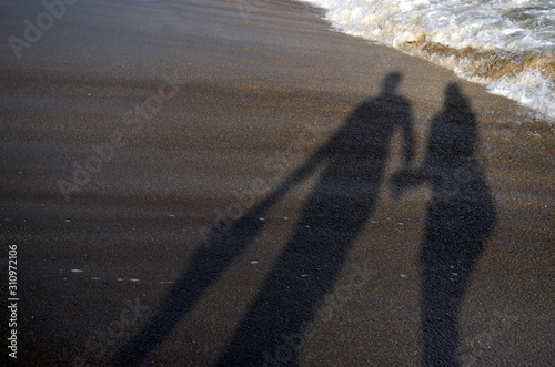 Sombras de una pareja proyectándose en la playa