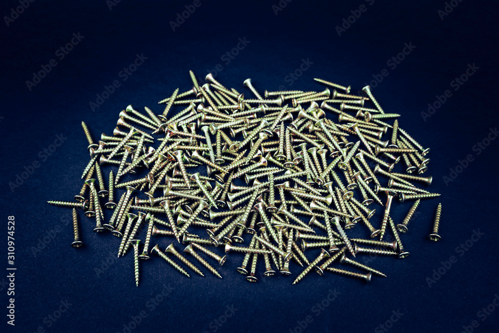 Tapping screws made of steel, metal screw, iron screw, chrome screw, wood screw, screws as a background. Deep blue background. 