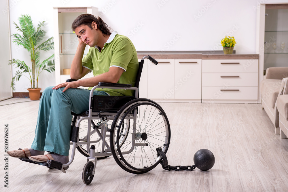 Young male invalid in wheel-chair suffering at home Young male invalid in wheel-chair suffering at home