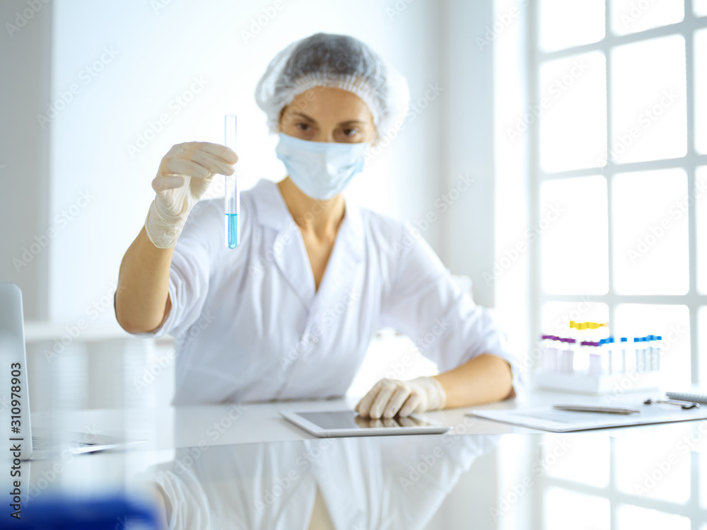 Professional female scientist in protective eyeglasses researching tube with reagents in laboratory. Concepts of medicine and research Professional female scientist in protective eyeglasses researching tube with reagents in laboratory. Concepts of medicine and research