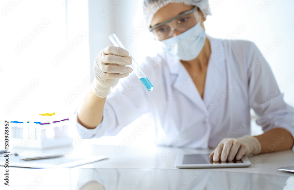Professional female scientist in protective eyeglasses researching tube with reagents in laboratory. Concepts of medicine and research Professional female scientist in protective eyeglasses researching tube with reagents in laboratory. Concepts of medicine and research