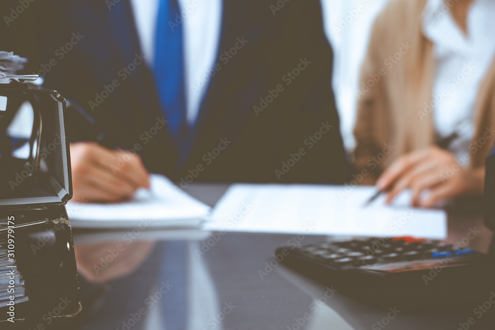 Binders with papers waiting to be processed with businessman or bookkeeper back in blur. Accounting planning budget. Audit, insurance and business concept Binders with papers waiting to be processed with businessman or bookkeeper back in blur. Accounting planning budget. Audit, insurance and business concept