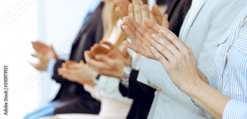 Business people clapping and applause at meeting or conference, close-up of hands. Group of unknown businessmen and women in modern white office. Success teamwork or corporate coaching concept