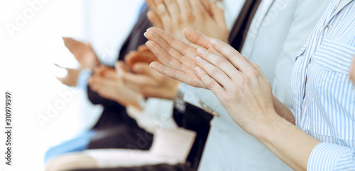 Business people clapping and applause at meeting or conference, close-up of hands. Group of unknown businessmen and women in modern white office. Success teamwork or corporate coaching concept