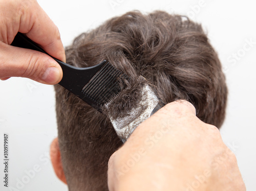 The hairdresser cuts the hair of a boy with a machine