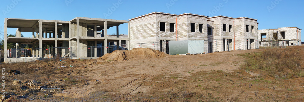 The building of unfinished rural houses from white bricks on sand hill panorama The building of unfinished rural houses from white bricks on sand hill panorama