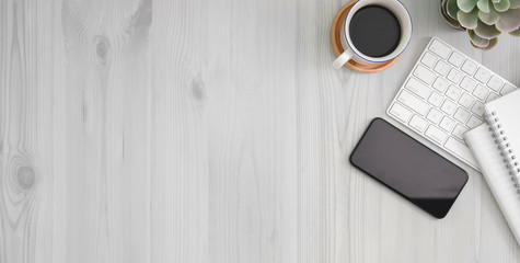 Cropped shot of comfortable workplace with smartphone, office supplies and copy space on white wooden