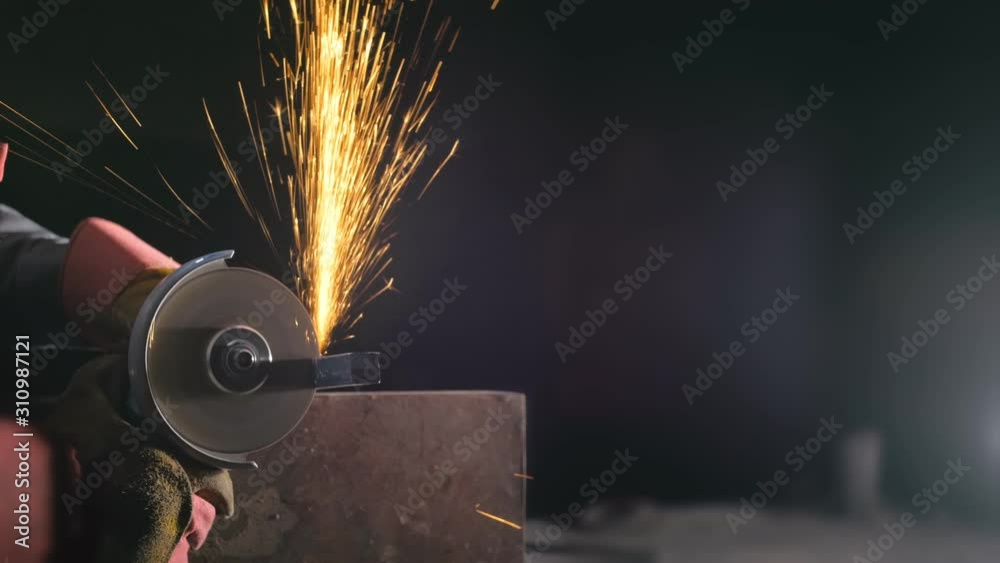 Forge workshop. Smithy manual production. Close up details of sparks, industrial worker using angle grinder and cutting steel. The blacksmith makes iron products for manufacture of fireplaces, stoves.