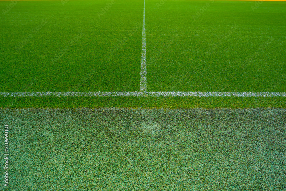 Top view of green football ground or soccer field with white stripes.