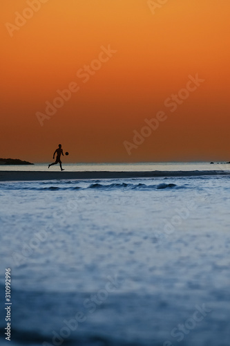 Silhouette a man with ball on the beach at sunset.