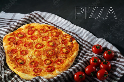 Freshly baked homemade pizza Margherita lies on a black background.