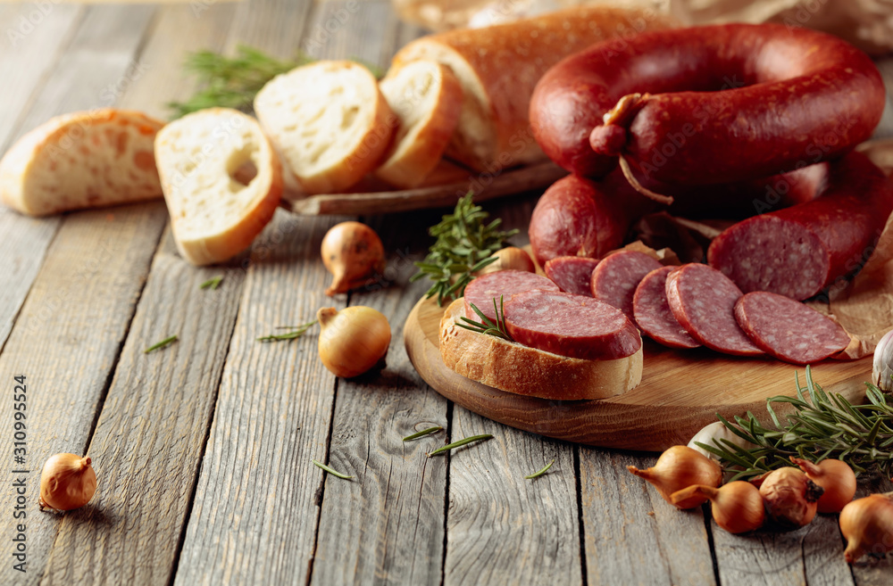 On a old wooden table sausage with bread, rosemary, onion and pepper. On a old wooden table sausage with bread, rosemary, onion and pepper.