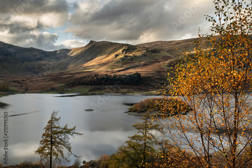 Stunning Autumn Fall landscape of Hawes Water with epic lighting and dramatic sunlight in Lake District