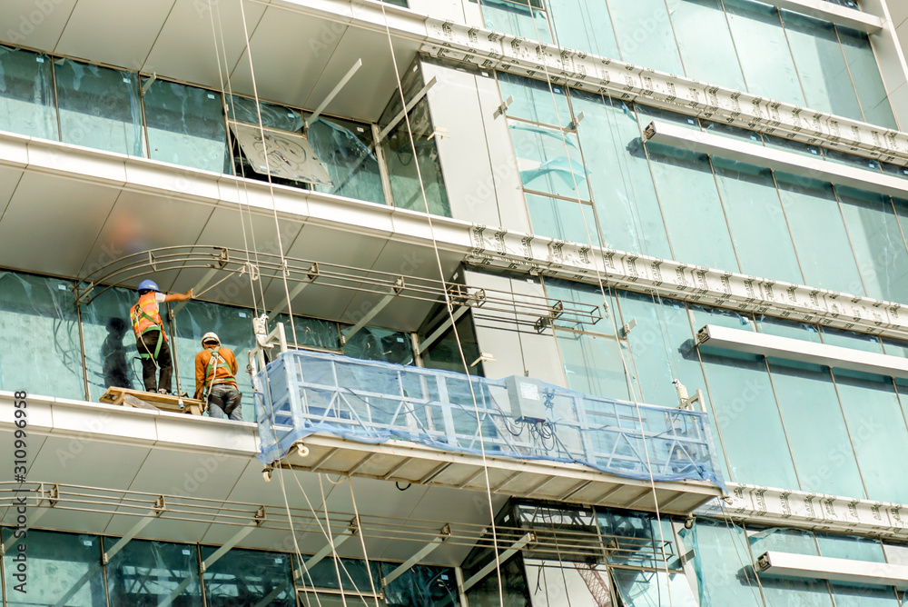 Thai workers are in stalling and cleaning mirrors of buildings.