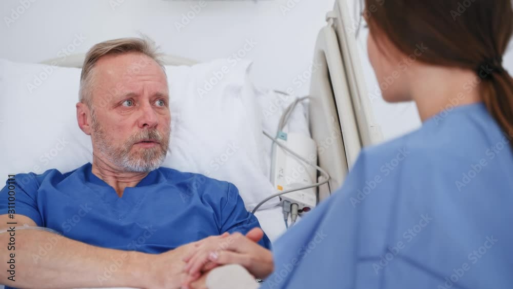 Senior male patient with female visitor in the hospital. Young woman talking to her sick father in clinic. Health care. Family support. Senior male patient with female visitor in the hospital. Young woman talking to her sick father in clinic. Health care. Family support.