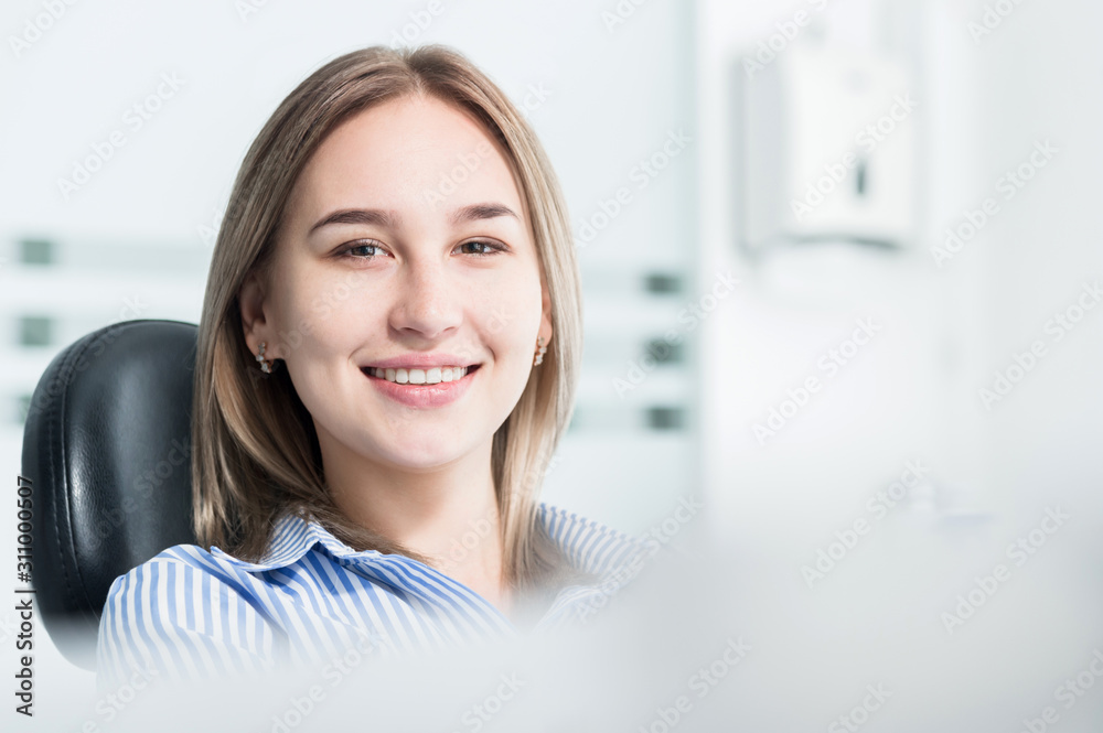 Portrait of an attractive smiling girl blonde in a dental chair. Happy customer dental cabinet