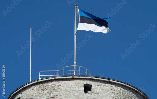 Fotografía Estonian flag on the tower against the blue sky on a bright Sunny day