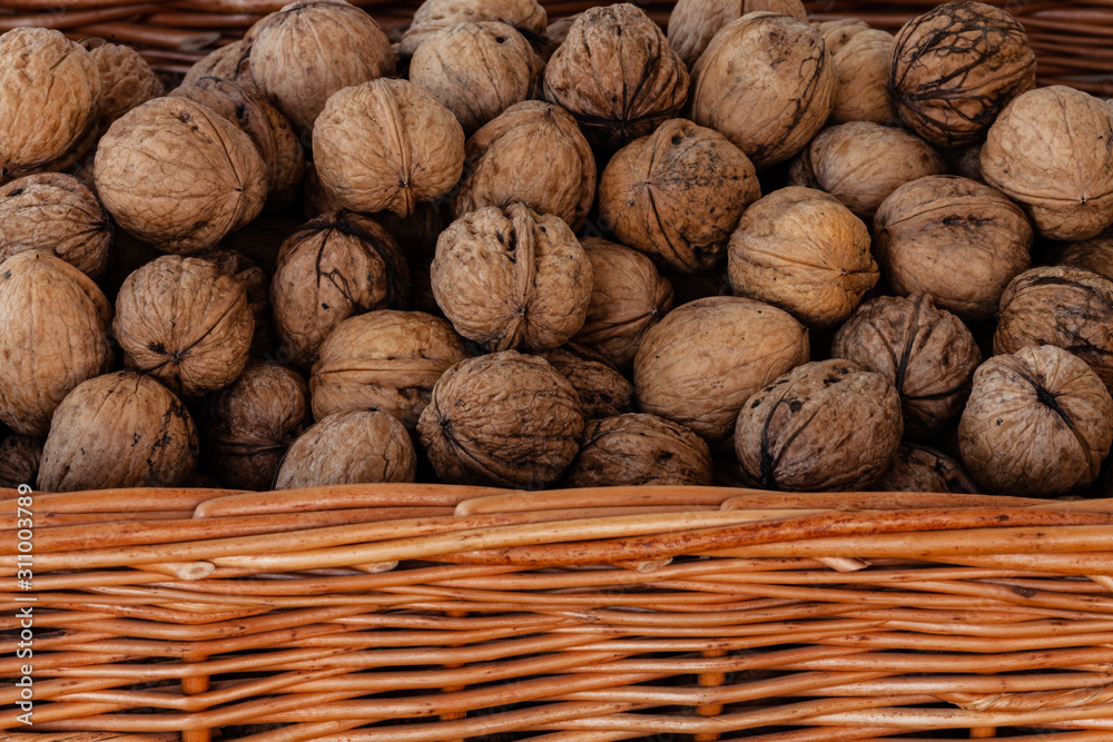 Wicker basket full of whole walnuts. Detailed closeup just edge of the basket visible. Wicker basket full of whole walnuts. Detailed closeup just edge of the basket visible.
