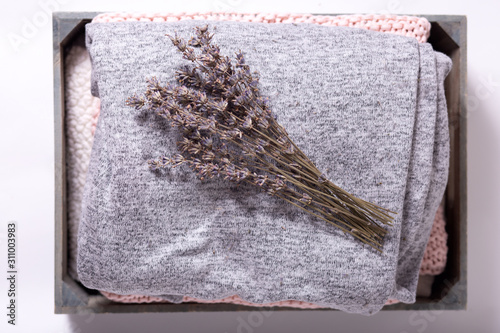 home comfort, textile, knitted, women's clothing, cotton, folded in a wooden box. dry lavender flowers, concept of order, comfort, close-up, light background, top view photo