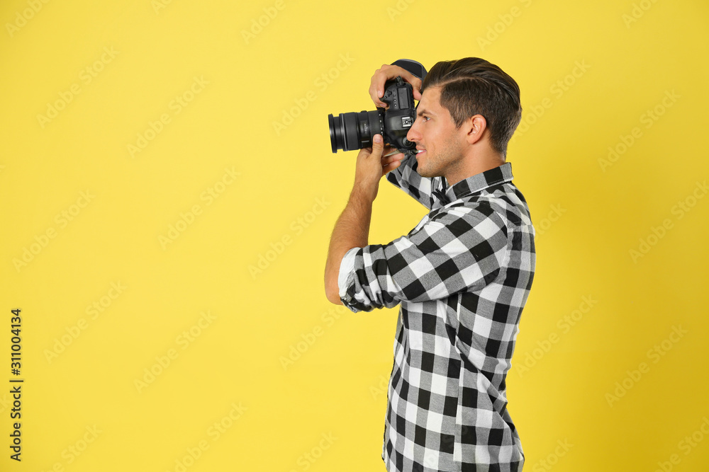Professional photographer working on yellow background in studio. Space for text - obrazy, fototapety, plakaty 