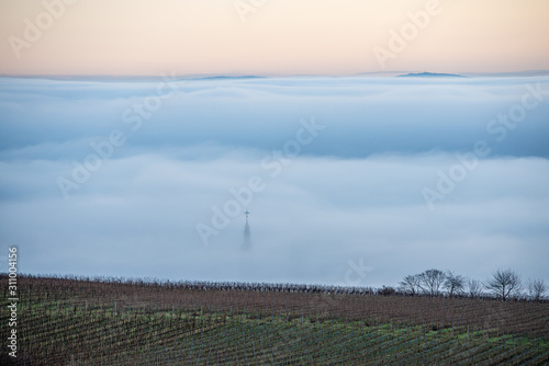 kirchturmspitze ragt aus dem nebel photo