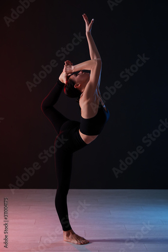 Young professional acrobat exercising in dark studio