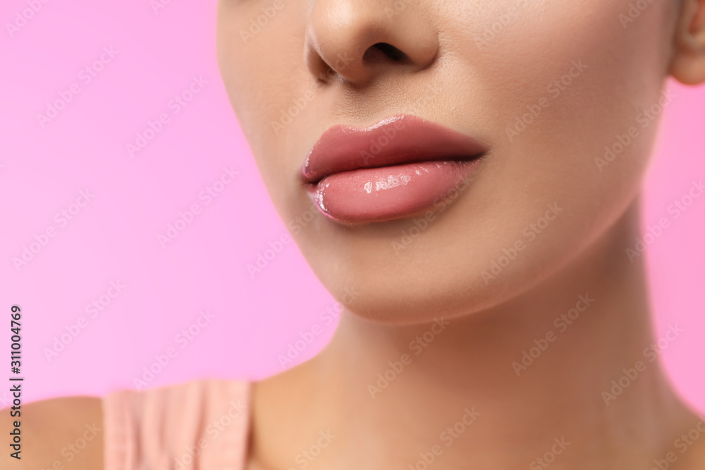 Woman with glossy lipstick on pink background, closeup
