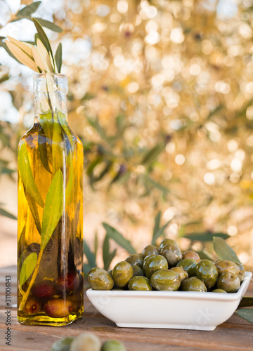 green olives and oil on table in olive grove