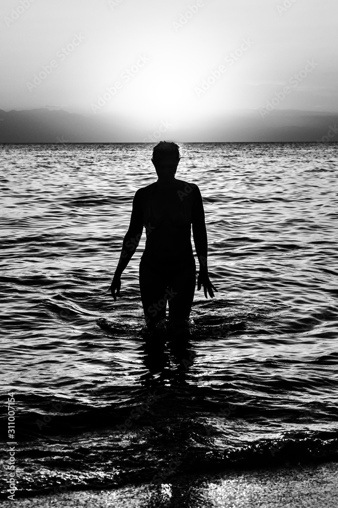 Young woman walking on water at sunset. Sunset and silhouette of a ...