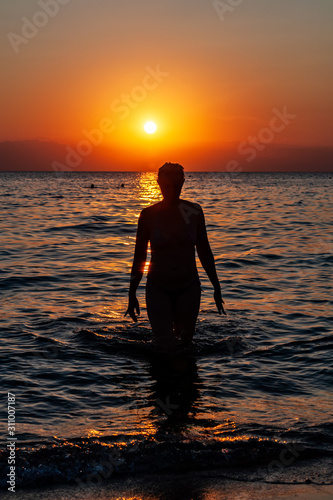 Obraz na płótnie Young woman walking on water at sunset