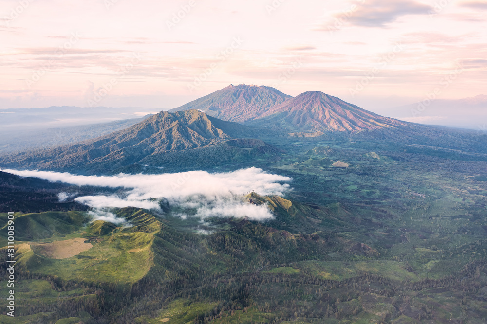 Stunning view of a beautiful mountain range surrounded by clouds during sunrise. Ijen Volcano complex. The Ijen volcano complex is a group of composite volcanoes located in East Java, Indonesia. Stunning view of a beautiful mountain range surrounded by clouds during sunrise. Ijen Volcano complex. The Ijen volcano complex is a group of composite volcanoes located in East Java, Indonesia.