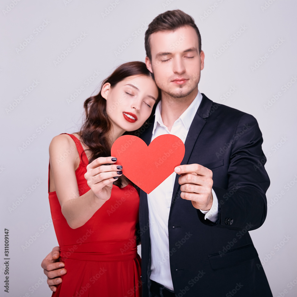 Sensual couple of newlyweds closed their eyes and holds a red heart.