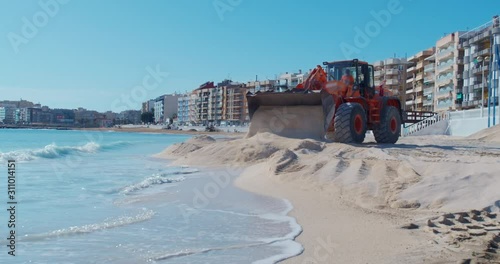 Construction loader works at a sand shore, expansion and improvement of the beach.