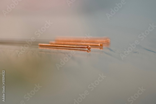 three copper wire acupuncture needles for moxa and moxibustion on a table with blurred backgroud