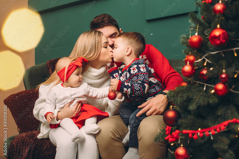 Beautiful mother in a white sweater. Family with christmas gifts. Brother with sister near christmas tree Beautiful mother in a white sweater. Family with christmas gifts. Brother with sister near christmas tree