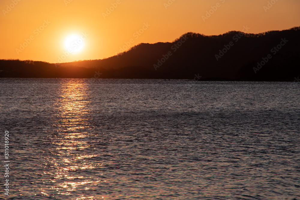 夜明けの太陽に照らされた湖面。北海道、屈斜路湖。