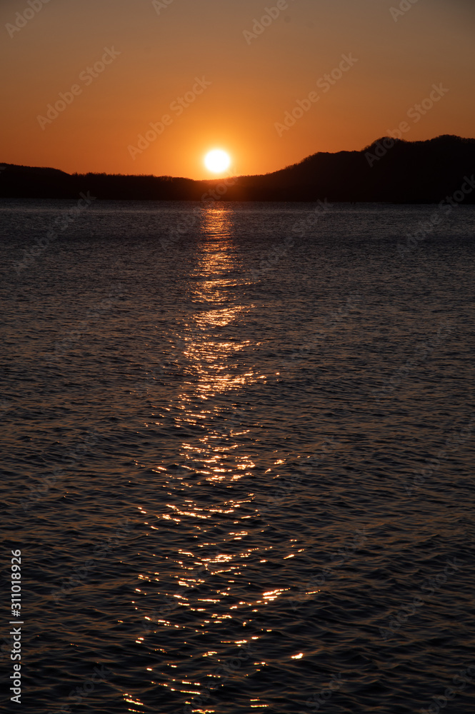 夜明けの太陽に照らされた湖面。北海道、屈斜路湖。