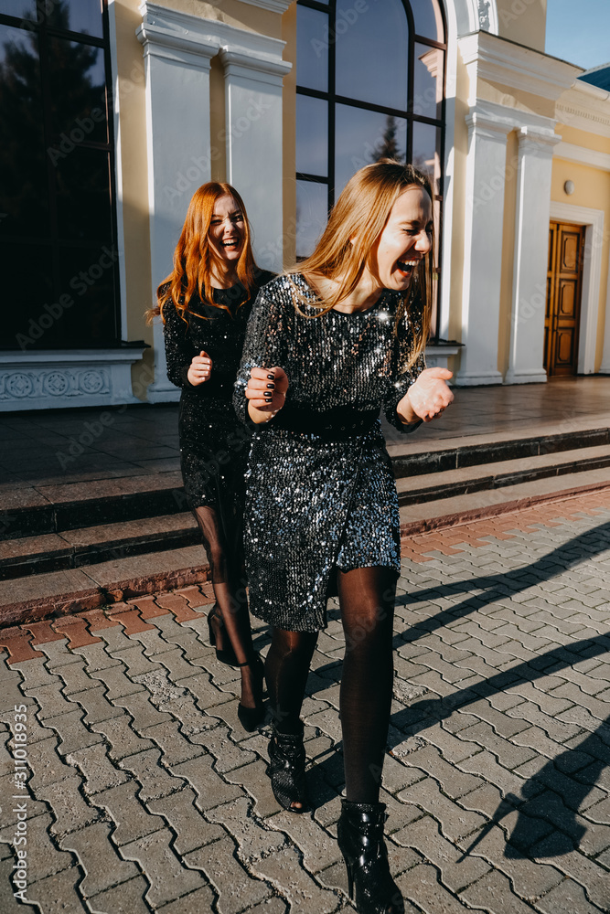 Foto Stock Evening party cocktail outfit ideas. What to wear. Trend and  fashion. Two Beautiful stunning young women in glitter sequins dress  outdoor lifestyle portrait | Adobe Stock