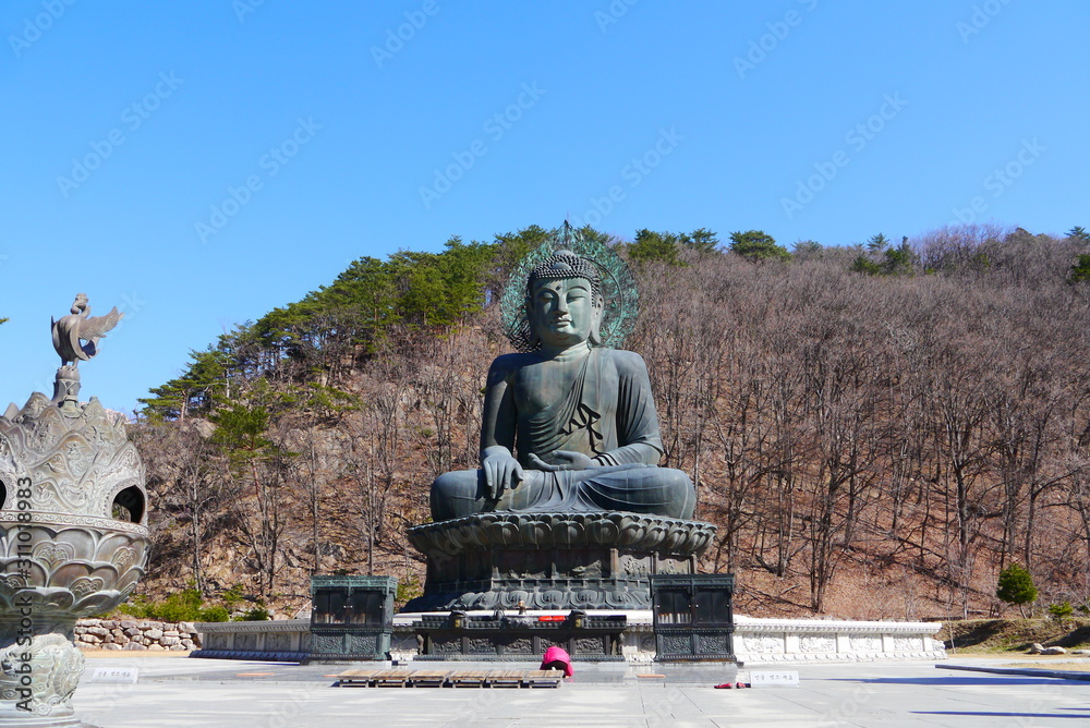 Fototapeta premium Tourists praying at The Great Unification Buddha (Tongil Daebul) at Shinheungsa temple, Seoraksan National Park, Sokcho, South Korea