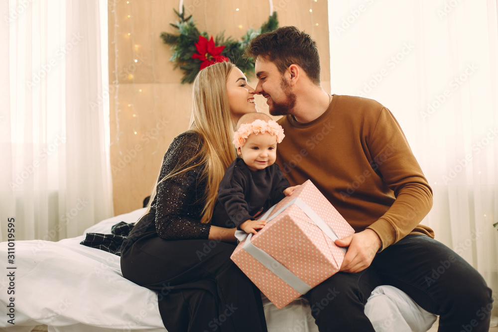 Beautiful mother in a black dress. Family sitting with christmas gifts. Little girls with arents Beautiful mother in a black dress. Family sitting with christmas gifts. Little girls with arents