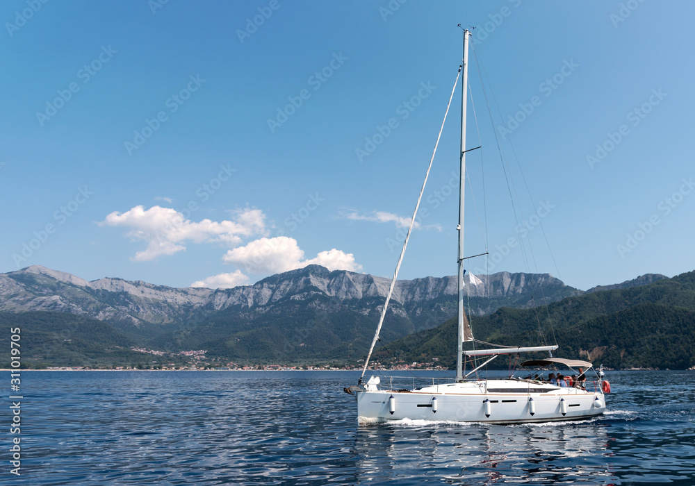 Sailing yacht in the sea against the backdrop of mountains at sunny day