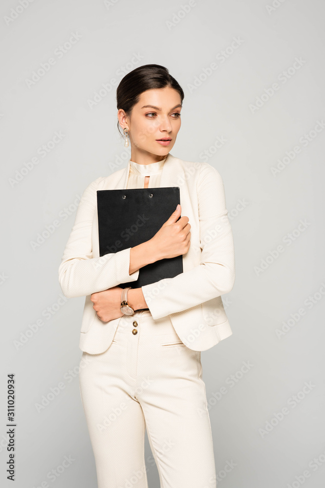 elegant confident businesswoman in white suit holding clipboard, isolated on grey elegant confident businesswoman in white suit holding clipboard, isolated on grey