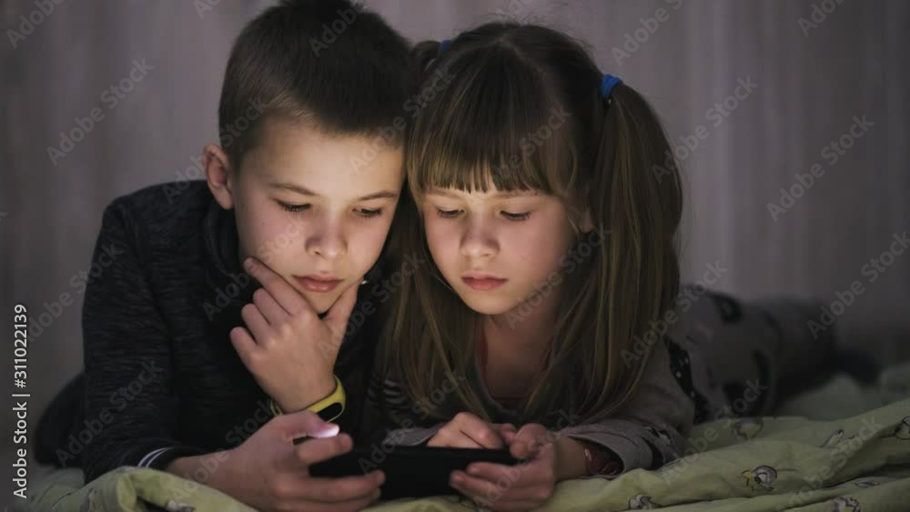 Two children brother and sister watching video on smartphone screen together.