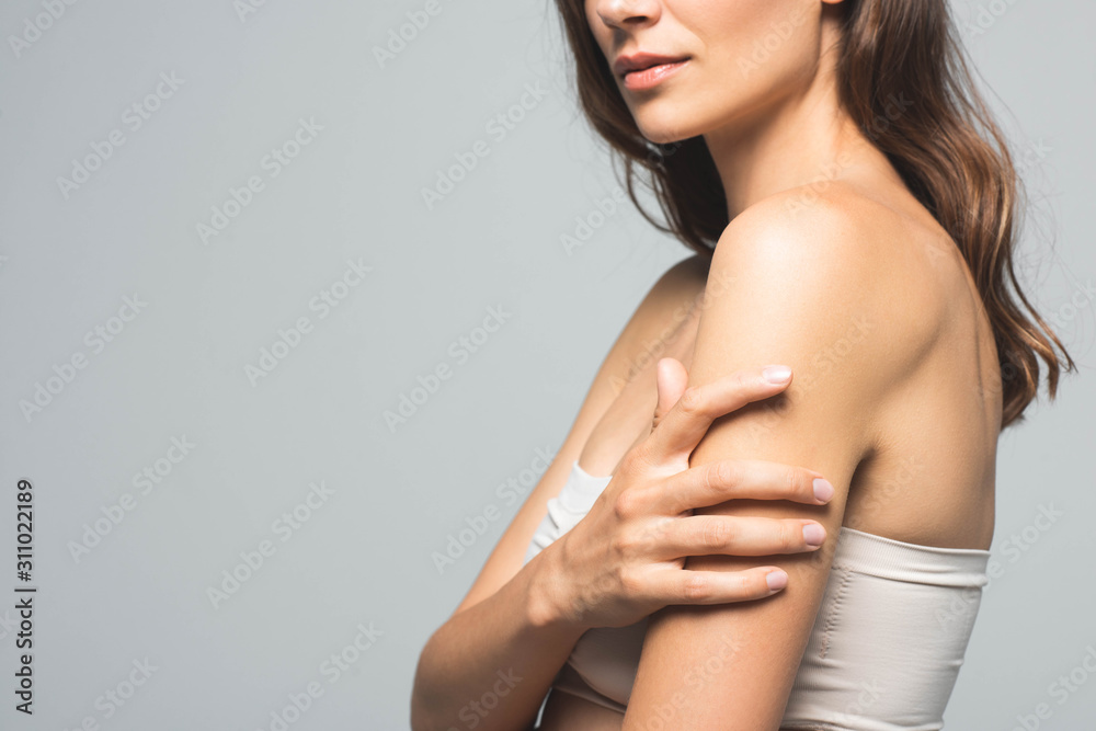 cropped view of attractive brunette woman with clean skin, isolated on grey cropped view of attractive brunette woman with clean skin, isolated on grey