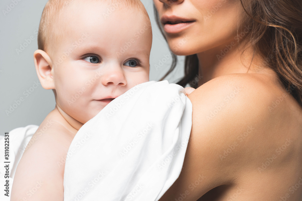 cropped view of naked mother hugging positive baby boy, isolated on grey cropped view of naked mother hugging positive baby boy, isolated on grey