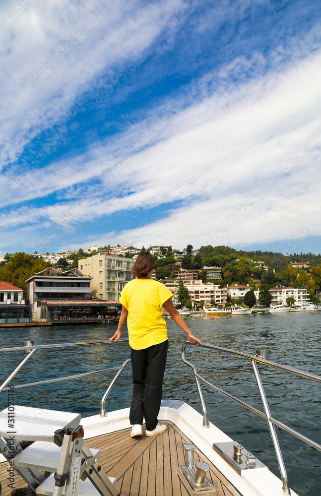Woman traveller in a yellow t-shirt on a private yacht during Bosphorus cruise in Istanbul Turkey.