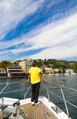 Woman traveller in a yellow t-shirt on a private yacht during Bosphorus cruise in Istanbul Turkey.
