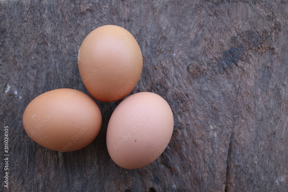 Three eggs on a wooden table being brought to cook Three eggs on a wooden table being brought to cook