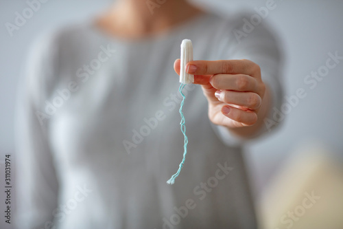Close up of a woman's hands which are holding a tampon. Tampo on womans hand before intravaginal aplication. Woman holds a tampon in toilet. Woman holds a tampon sitting in a toilet