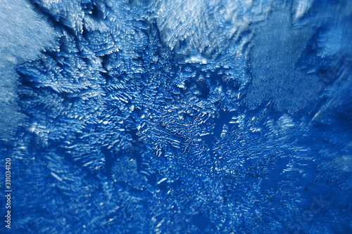 Beautiful frozen patterns on glass, macro photo. The concept of winter, the beauty of nature, frost, cold. Abstract background image. Trendy color classic blue.